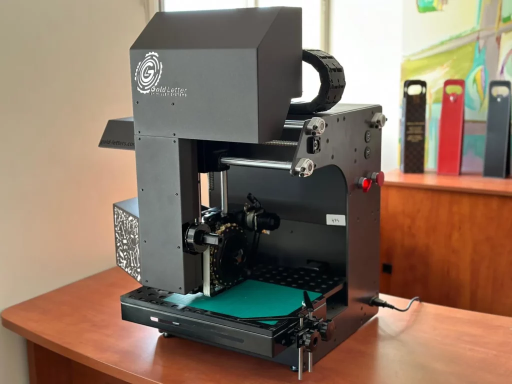 Gold Letters digital embossing and foil stamping machine in a studio workspace.