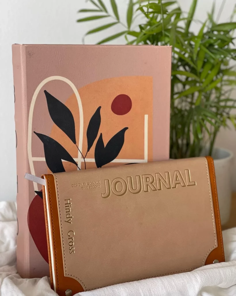 Personalized journal with gold foil embossing placed in front of an illustrated hardcover book.