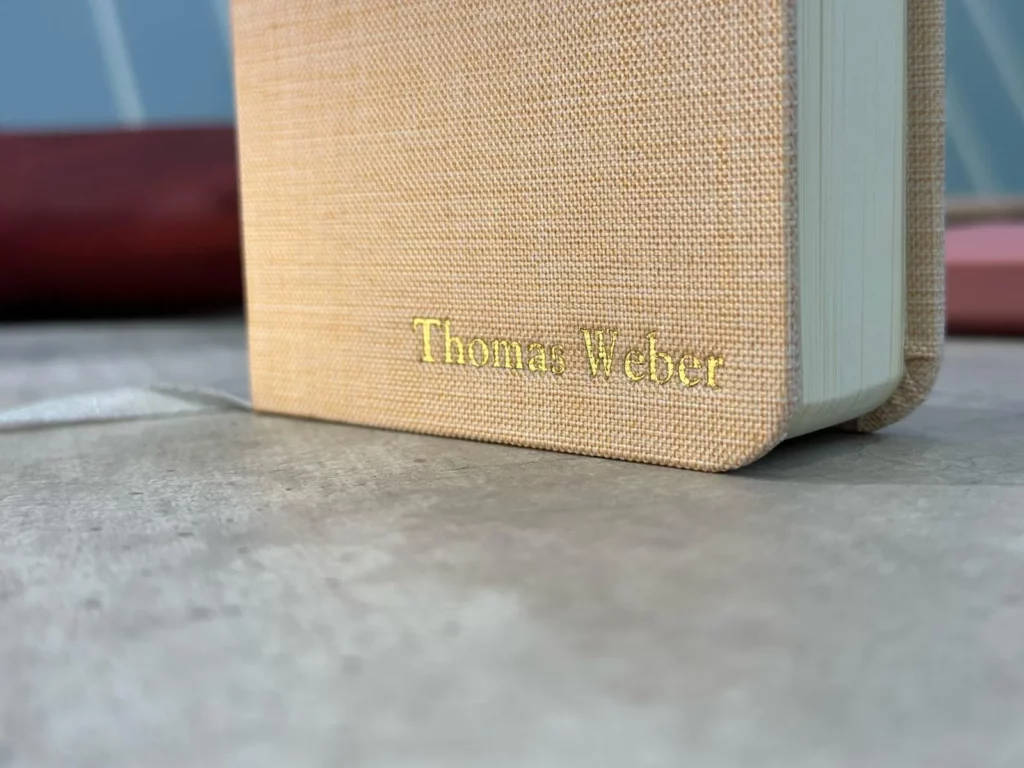 Close-up of beige fabric-covered book with gold foil stamped personalized name.